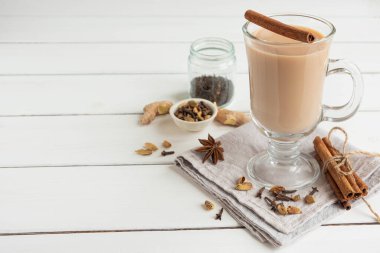 Bir bardak aromatik baharat ve sütle demlenmiş sıcak Hint masala çayı. Beyaz tahta arkaplan, boşluğu kopyala