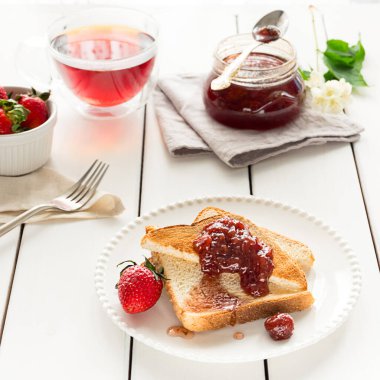 Toasted bread slices with strawberry jam and a jar of jam