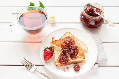 Toasted bread slices with strawberry jam and a jar of jam