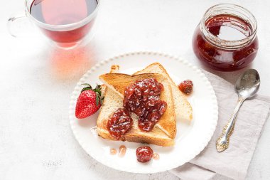 Toasted bread slices with strawberry jam and cup of tea