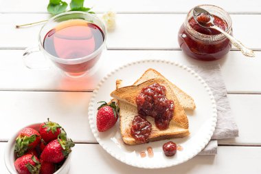 Toasted bread slices with strawberry jam and a jar of jam