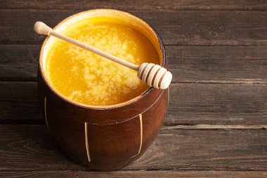 Tahta bir kavanozda bal ve bal kaşığı