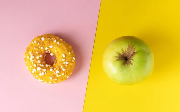 분홍색 과 노란색 배경에는 도넛 과 사과가 있습니다. 식생활 개념. — 스톡 사진