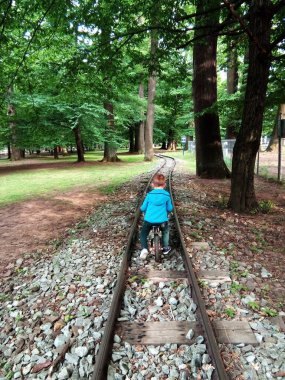 Bir çocuk demiryolunda bisiklet sürüyor.