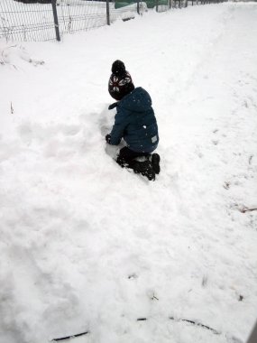 Bir çocuk karda oynuyor.