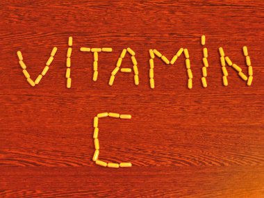 Ahşap zemin üzerinde organik C vitamini kapsüllerinden yazılmış C vitamini metni