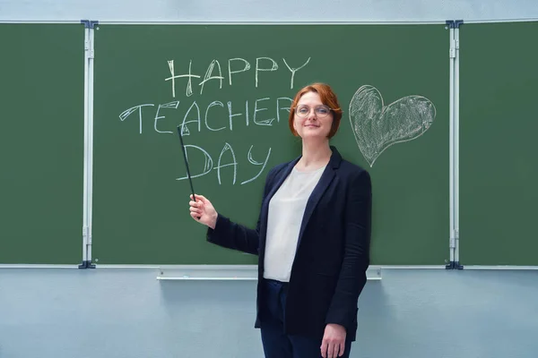 A smiling teacher shows with a pointer to the text 