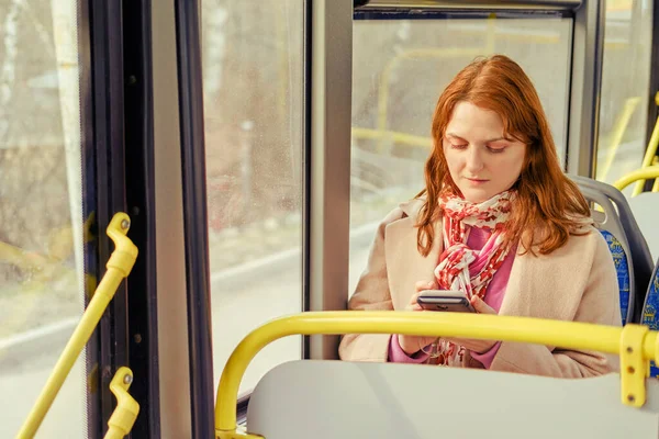 A woman rides a bus and looks at the route on her phone