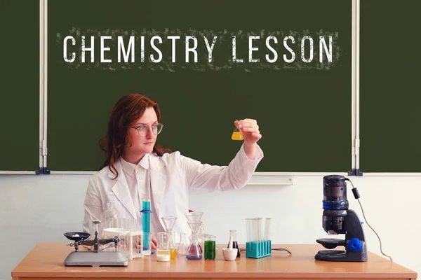 The chemistry teacher conducts tests with reagents sitting at the school table. Text on the blackboard \