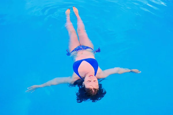 Girl in swimsuit on back in blue pool