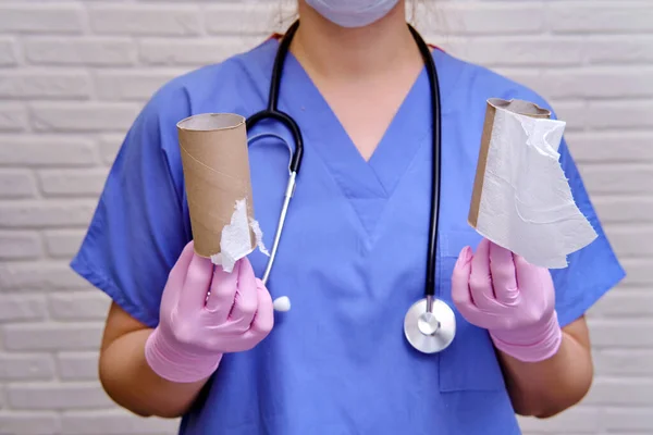 A doctor in medical gloves is holding a run-out toilet paper. Problems with toilet paper in the coronavirus epidemic, the concept of diarrhea