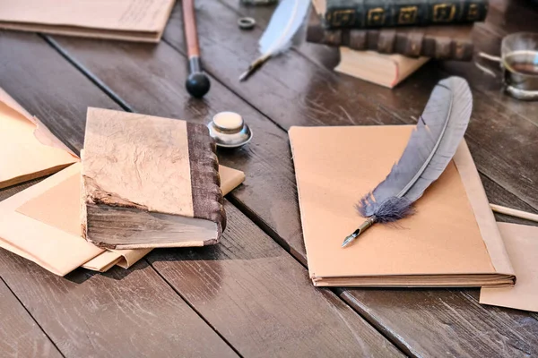 Table with old writing utensils in the 18-19 century. Notepad, paper and feather for writing ink, close-up.