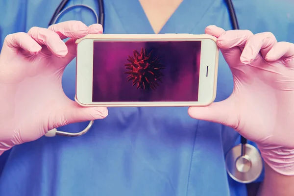 Doctor with a phone in her hand, close up. Concept of remote care for patients with coronavirus, helps patients through the Internet. Stay at home.