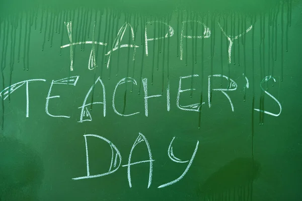 The inscription Happy Teacher Day on the blackboard is washed off with drops of water, the concept of the end of the holiday