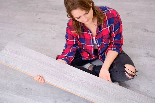 A woman thinks how to install a floor covering when repairing a house