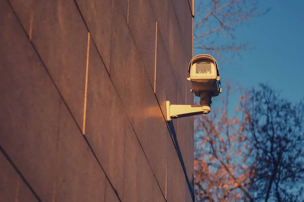 Surveillance camera on the wall of the house. Close-up camera on street in the evening sunset light