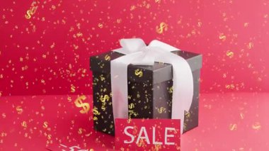 Kırmızı kurdeleli hediye kutusu ve kırmızı arkaplanlı altın fiyonk.