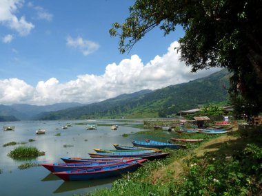 Phewa Gölü, Pokhara, Nepal 'de dağları olan renkli kayıklar.