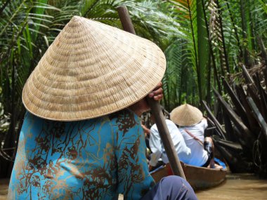 Vietnam 'da Mekong' da tipik konik şapkalı ve mavi gömlekli Vietnamlı bir kadın kano kullanıyor. Yüksek kalite fotoğraf