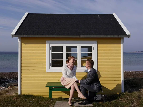 Jonge man knielen voor vriendin samen lachen op strand hut, Aero Stockafbeelding