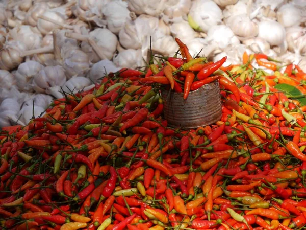 Fresh bright red spicy peppers and garlic cloves piled on market stall. High quality photo