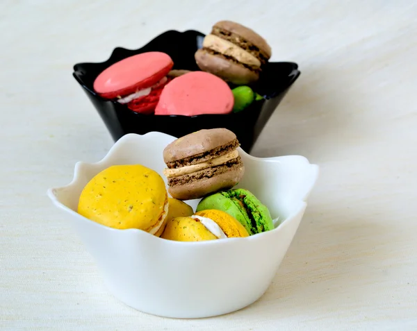 Galletas de macarrones de colores dulces en cuencos blancos y negros —  Fotos de Stock