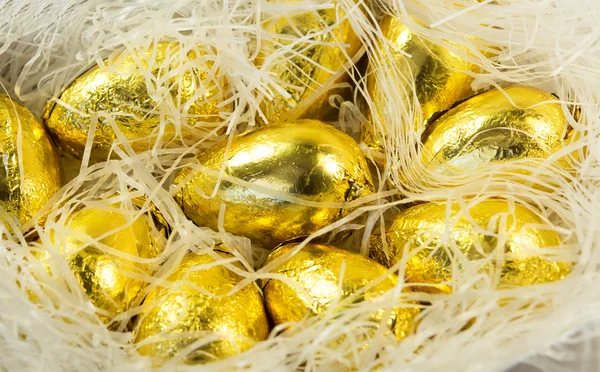 Czekoladowe jaja wielkanocne w jasny złoty okładka — Zdjęcie stockowe
