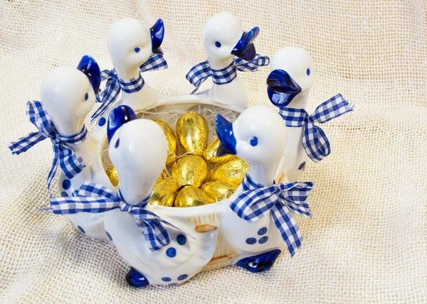 Huevos de Pascua de chocolate en cubierta brillante en blanco con jarrón azul con figuras de patos Imagen de stock