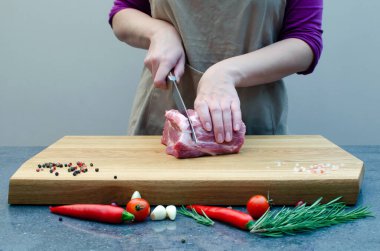 Şef Kasap mutfakta bıçakla domuz eti kesiyor, yemek pişiriyor.