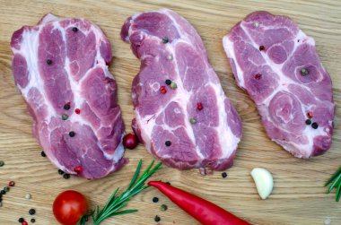 Kırmızı ve yeşil biberlerin yanında üç sulu biftek var.