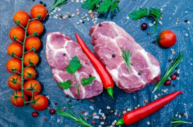 Siyah mermer üzerinde baharatla kızarmadan önce iki sulu domuz bifteği.