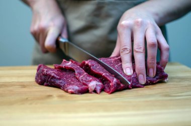 Kadınların elleri güzel kırmızı et parçalarını bıçakla kesiyor. Biftek, pirzola. Et parçaları..