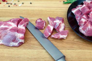 Kesme tahtasındaki mutfak bıçağıyla dilimlenmiş çiğ et, dilimlenmiş et dilimlenmiş siyah tabak..