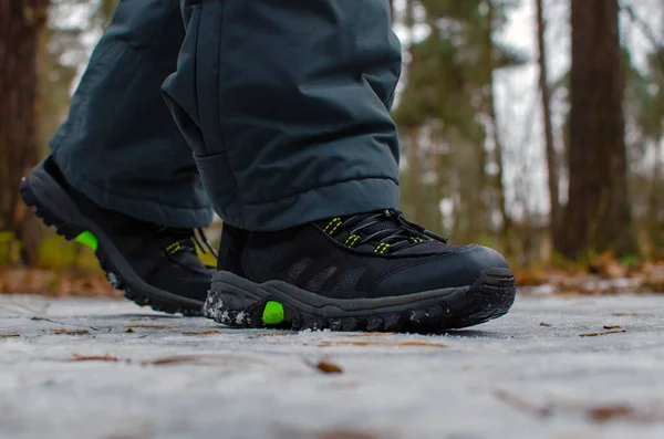 Um homem caminha em uma estrada escorregadia, a primeira neve no parque, sapatos de inverno, a estrada está coberta com gelo escorregadio. — Fotografia de Stock