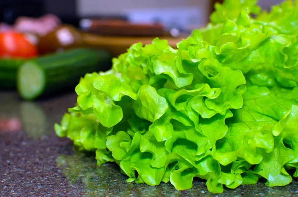 Groene sla bladeren op een keukenachtergrond. Groene salade achtergrond. Close-up — Stockfoto