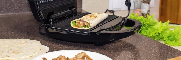 Roll of pita bread, vegetables and chicken. Cooking on an electric grill. Kebab, shawarma. — Stockfoto