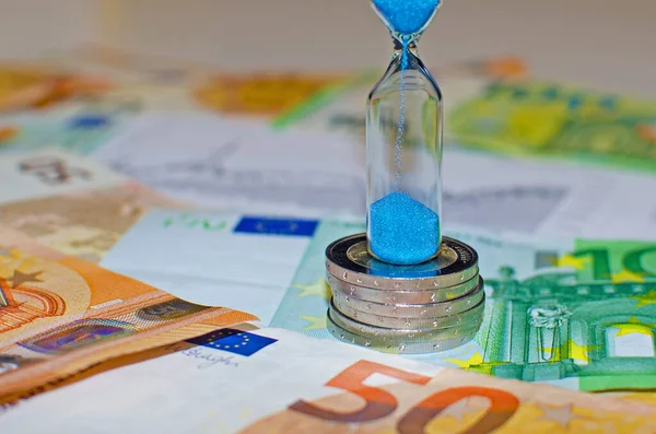 Hourglass on the background of euro banknotes. Concepts of investment, retirement money and money movement over time —  Fotos de Stock