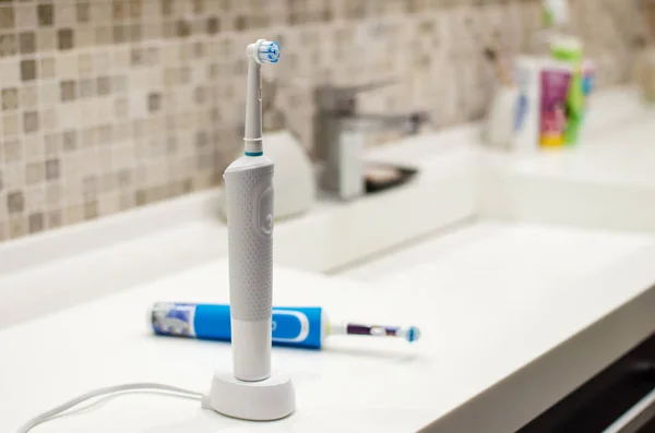 Rechargeable, electric toothbrush, close-up. Against the backdrop of a bathroom in white. — Stock Photo, Image