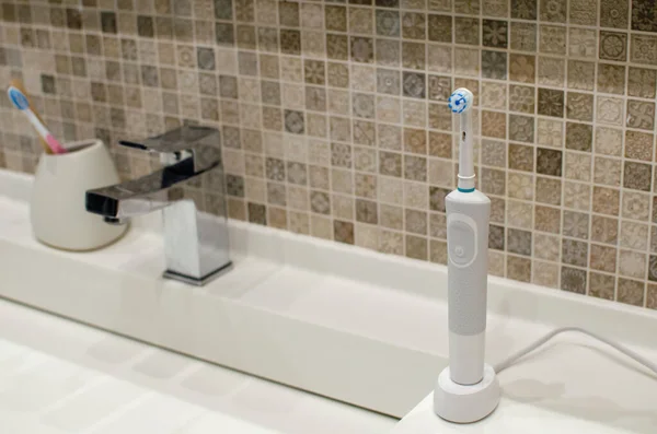 Rechargeable, electric toothbrush, close-up. Against the backdrop of a bathroom in white. — Stock Photo, Image