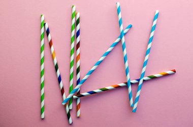 Saman içmek. Yaz kokteylleri için renkli pipetler içmek. Fotokopi alanı olan pembe bir arka planda..