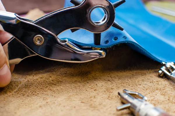 Leather goods manufacturing process. Tools for sewing bags, wallets, clutches. Colored pieces of leather. Close-up