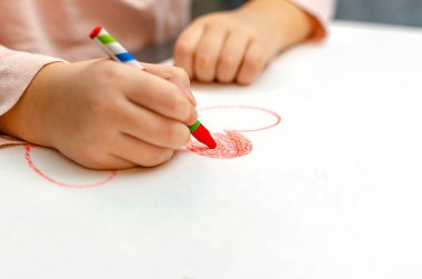 Küçük bir kız kırmızı tebeşirli bir kalp çiziyor. Yüksek açılı, seçici odaklı bir resim. Sevgililer Günü konsepti