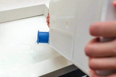Kurutucudan çıkan konteynırda bir kadın kurutucudaki çamaşırları kuruttuktan sonra biriken suyu boşaltıyor..