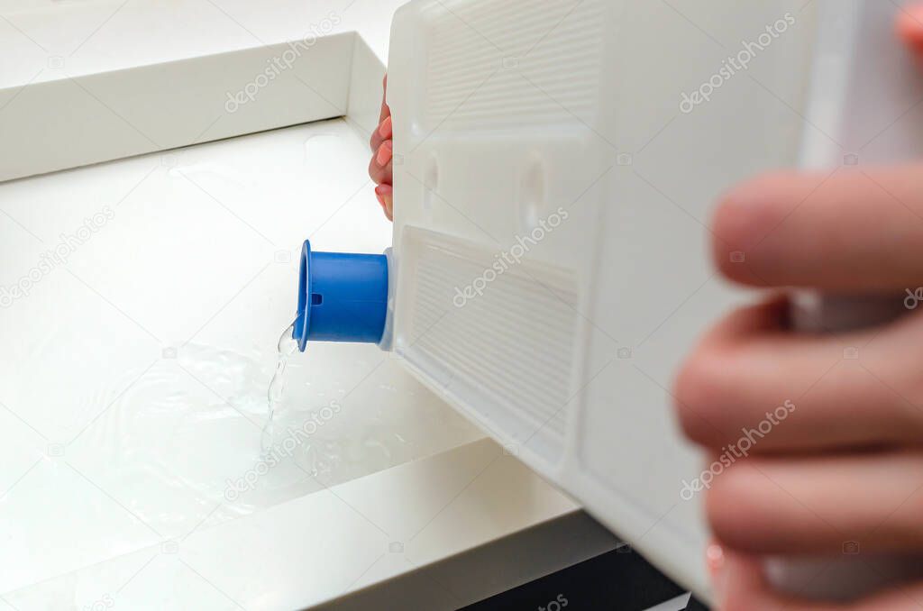 Condensate container from the dryer, a woman drains the accumulated water after drying clothes in the dryer.