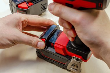 Bir marangozun elindeki pilin üzerindeki elektrikli tornavida. Erkek eller elektrikli tornavida tutuyor. Pil Değiştirme