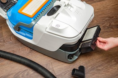 Modern endüstriyel elektrik süpürgesinin hava filtresinin elle değiştirilmesi. Kadınlar elektrik süpürgesinin filtresini çıkarıyorlar.