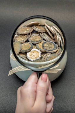 Avro paralarıyla dolu bir kumbarayı hedef alan büyüteç. Tasarruf ve birikim kavramı