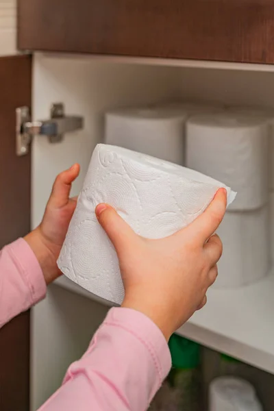 Papel higiénico, rolo de papel higiénico na mão. Existências de papel higiénico. A rapariga põe papel higiénico no armário. Foto vertical — Fotografia de Stock
