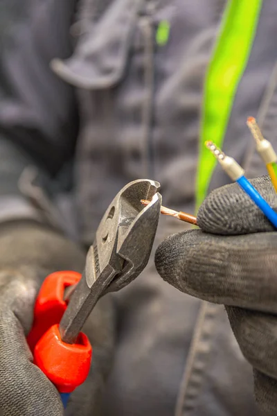 Électricien coupe les fils électriques avec des pinces, installation d'appareils électroménagers, outils électriciens. Photo verticale — Photo