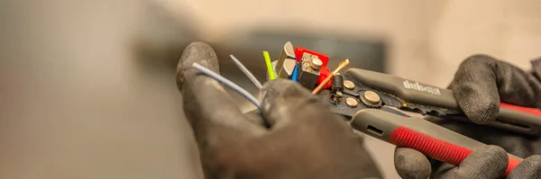 Des décapants. L'électricien nettoie l'isolant protecteur du fil à l'aide d'un décapant. Le processus de connexion des fils. gros plan — Photo